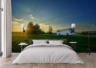 White bus traveling on the road in a rural landscape at sunset Wall mural