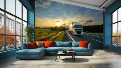 White truck driving on the asphalt road in rural landscape at sunset Wall mural