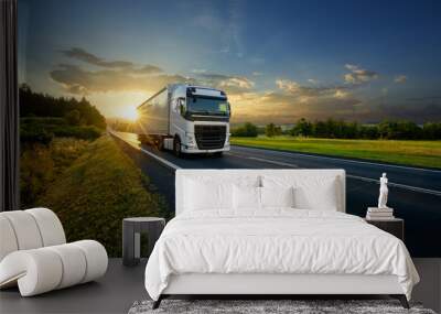 White truck driving on the asphalt road in rural landscape in the rays of the sunset Wall mural