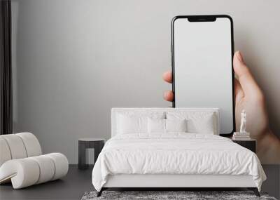 Woman holding smartphone with blank white screen on grey background Wall mural