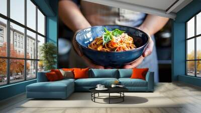 A chef holding a bowl of delicious pasta. Wall mural