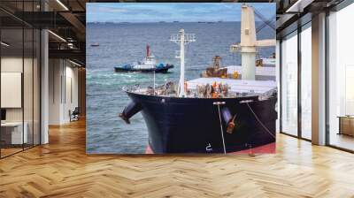 Tug boats are towing and assist the big vessel for unberth from port of thailand. Wall mural