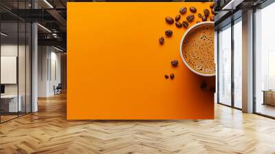 Cup of coffee and scattered beans on an orange background. Wall mural