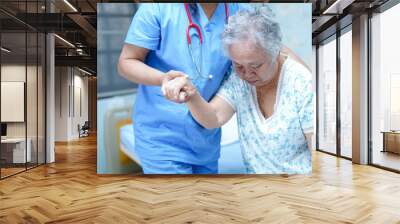 Asian nurse physiotherapist doctor care, help and support senior or elderly old lady woman patient get up from bed at hospital ward : healthy strong medical concept. Wall mural