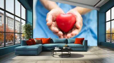 Doctor holding a red heart in hospital, healthy strong medical concept. Wall mural