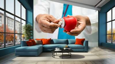 Doctor holding a red heart in hospital ward, healthy strong medical concept. Wall mural