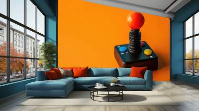 A retro arcade joystick placed on a bright orange background. Wall mural