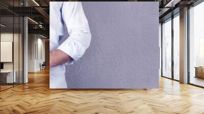 A man in a shirt holds a Bible book in his hands. On a gray background. Pastor. Prayer. Wall mural