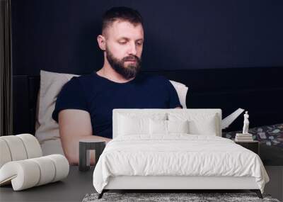 A young man sits on the bed and reads the Bible book. Prayer Wall mural