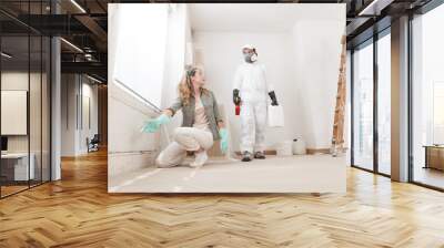 Concerned woman at a home renovation site shows a mold problem to a professional worker using products for mold remediation treatment. Concept of wall painting, cleaning, and mold removal service Wall mural