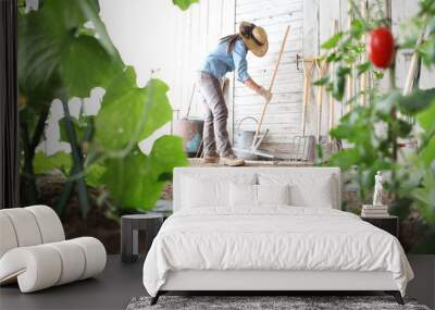 woman in the vegetable garden with rake from the wooden wall of tools, healthy organic food produce concept Wall mural