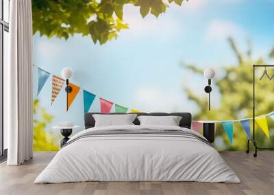 Vibrant summer celebration: colorful pennant string decoration swinging amidst green tree foliage, against blue sky - festive banner with copy space Wall mural