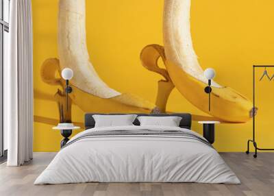 Two bananas on a yellow background peeled to half. Creative minimal surreal concept. Women's shoes and feet. Wall mural