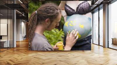 Young Man finger painting on a woman's pregnant belly Wall mural