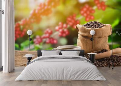 Cup of coffee and coffee beans in burlap sack on coffee tree background.. Wall mural