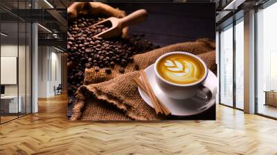 Cup of coffee latte and coffee beans in burlap sack on old wooden background Wall mural