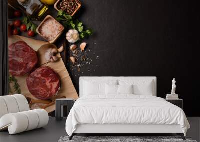 Fresh raw pieces of beef meat with ingredients for cooking on panorama black stone background Wall mural