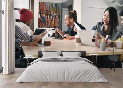 Group of young businesspersons having discussion and sharing opinions in meeting at office Wall mural