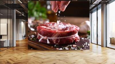 Hand sprinkling salt on fresh raw beef meat on a cutting board Wall mural