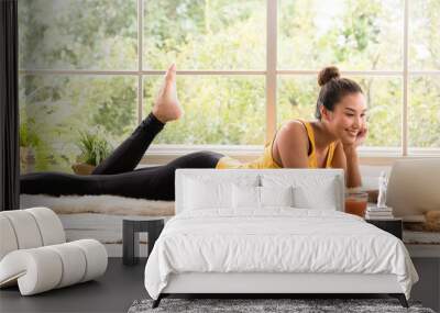 Healthy Asian woman lying on the floor eating salad and looking at laptop computer Wall mural