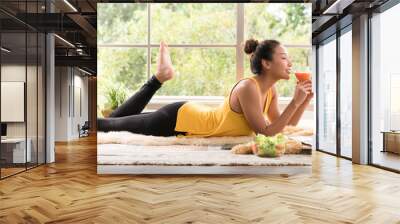 Healthy Asian woman lying on the floor eating salad looking relaxed and comfortable Wall mural