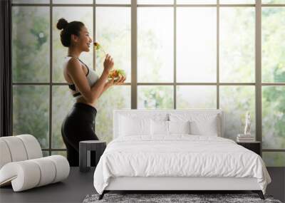 Healthy Asian woman standing and holding a salad bowl looking relaxed and comfortable Wall mural