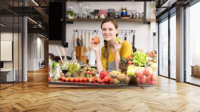 Healthy young woman in a kitchen preparing fruits and vegetables for healthy meal and salad Wall mural