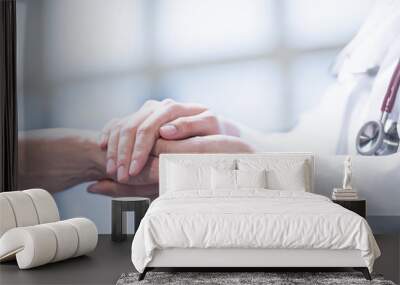 Medical doctor reassuring patient by holding patient’s hands in hospital setting Wall mural