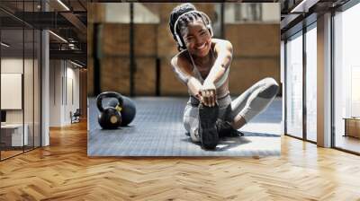 Portrait of woman stretching with music at gym, audio podcast for workout motivation and happy about fitness training on floor at health club. African athlete or sports person doing exercise Wall mural