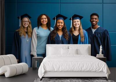 Group of young multicultural graduation students standing together against blue wall with cloak and graduation hat Wall mural