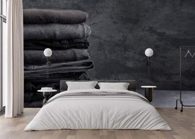 A stack of neatly folded dark clothes isolated on a black gray background close-up Wall mural