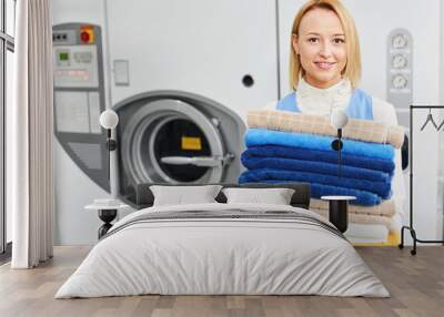 Girl worker holding a Laundry service clean towels and smiling Wall mural