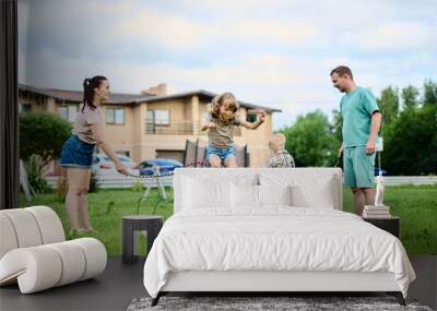 Happy family spending weekend in their backyard jumping rope and playing ball Wall mural