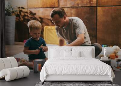 Little boy with his dad playing with toys at home. Happy father and son spending time together Wall mural