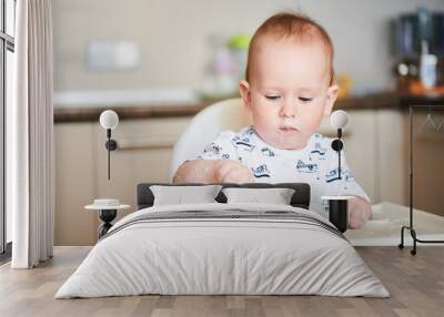 One year old boy learning to eat while sitting in the highchair Wall mural