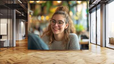 Smiling young woman with glasses having a conversation in a cozy cafe setting. Wall mural