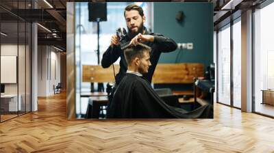 The Barber man in the process of drying a client's hair with a Hairdryer at the hairdresser Wall mural