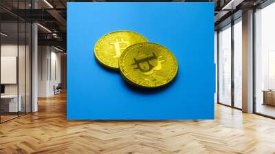 Two golden bitcoins isolated on blue background close-up with copy space, concept of growth and fall of cryptocurrency Wall mural