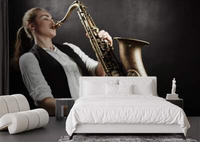 Young woman with saxophone on black background Wall mural