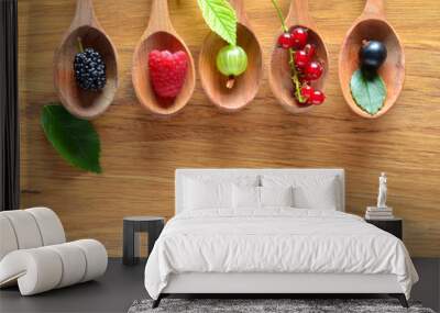 Fresh wild berries in ceramic spoons on wood background. Healthy food. Agriculture, Gardening, Harvest Concept. Background with space for text. Wall mural