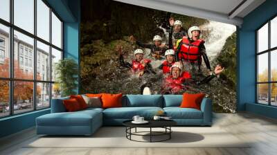 A group of adventurous individuals wearing helmets and using machinery to navigate a dynamic river canyon in Ecuador during a thrilling canyoning expedition. Wall mural