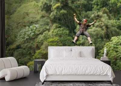 A group of people zip lining through the lush canopy of an Ecuadorian rainforest, surrounded by towering trees and vibrant green foliage. Wall mural