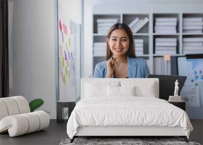 Asian business woman standing holding laptop in office. Wall mural