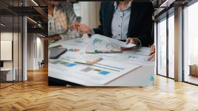 Business team reviewing financial documents with charts and graphs on a table during an office meeting Wall mural