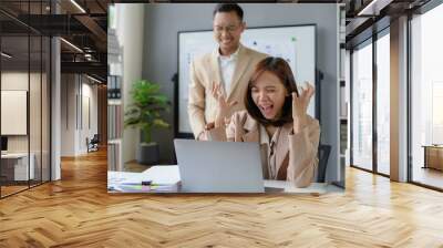 Excited businesswoman celebrating success with laptop in office Wall mural