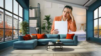 Exhausted businesswoman holding her head, feeling tired and suffering from a headache while calculating monthly budget and expenses at office desk Wall mural