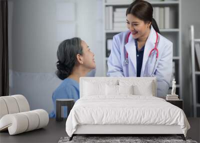 Friendly doctor consulting with a senior patient in a hospital room, discussing treatment and care options with a smile. Wall mural