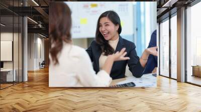 Happy two young Asian business women discuss investment projects and new business planning strategies at the office happily and without stress. Wall mural