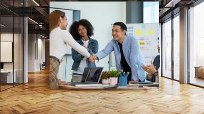 Happy young Asian businessman shaking hand congratulating success of the other business executives shake hand to congratulate on the future business cooperation agreement. Wall mural