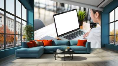 Side view of a businesswoman working on a laptop blank white screen at office. Mock up. Wall mural